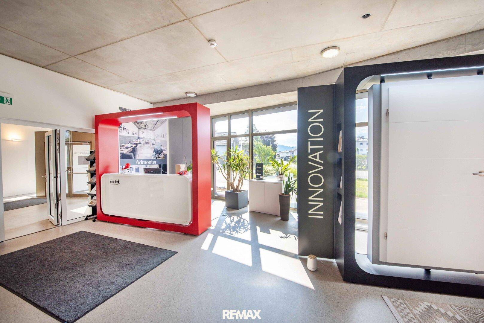 Heller, moderner Empfangsbereich oder Ausstellungsraum mit großen Fenstern und Designelementen.