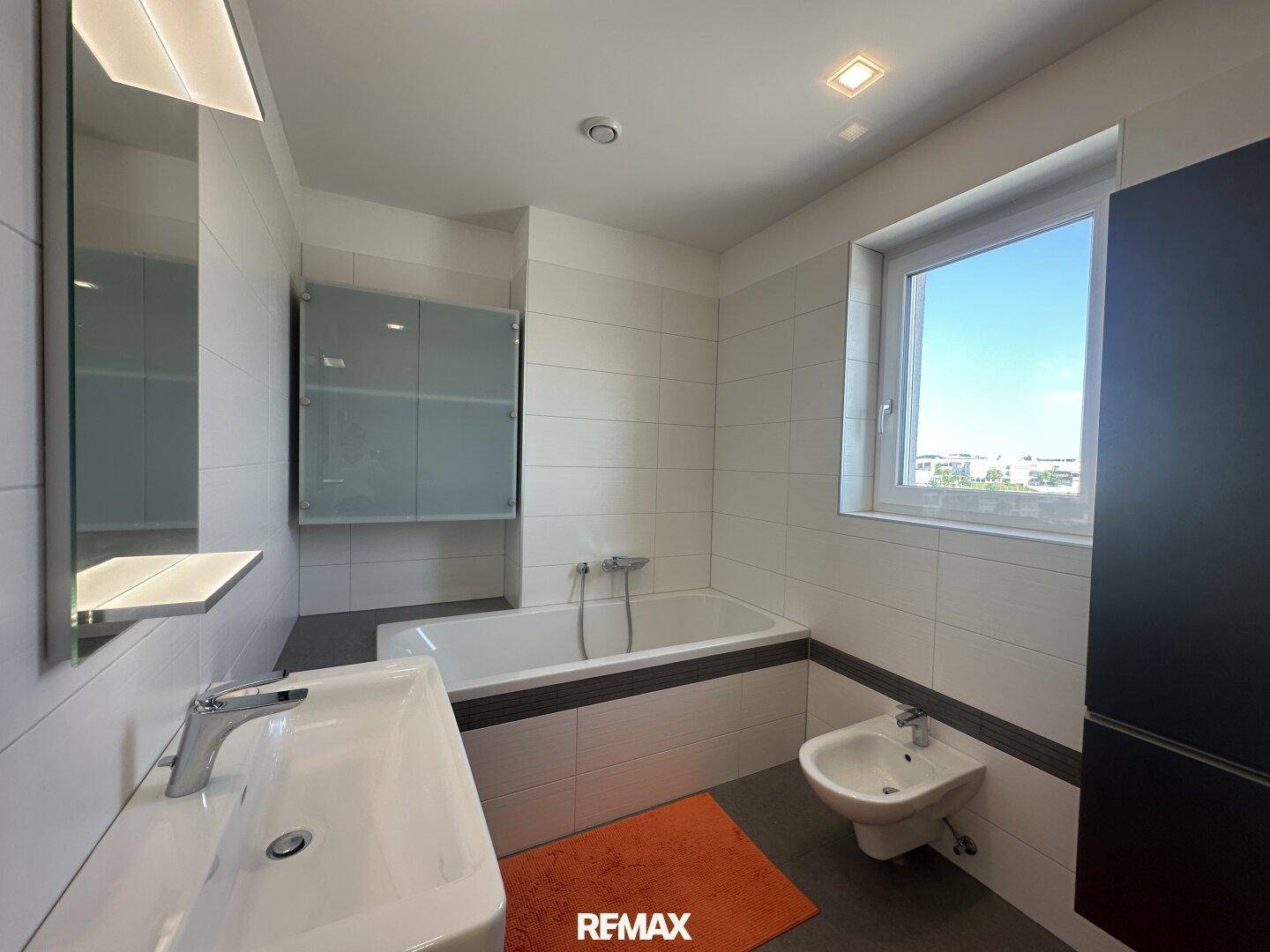 Modernes Badezimmer mit Badewanne, Bidet, Einzelwaschbecken und einem Fenster für Tageslicht.
