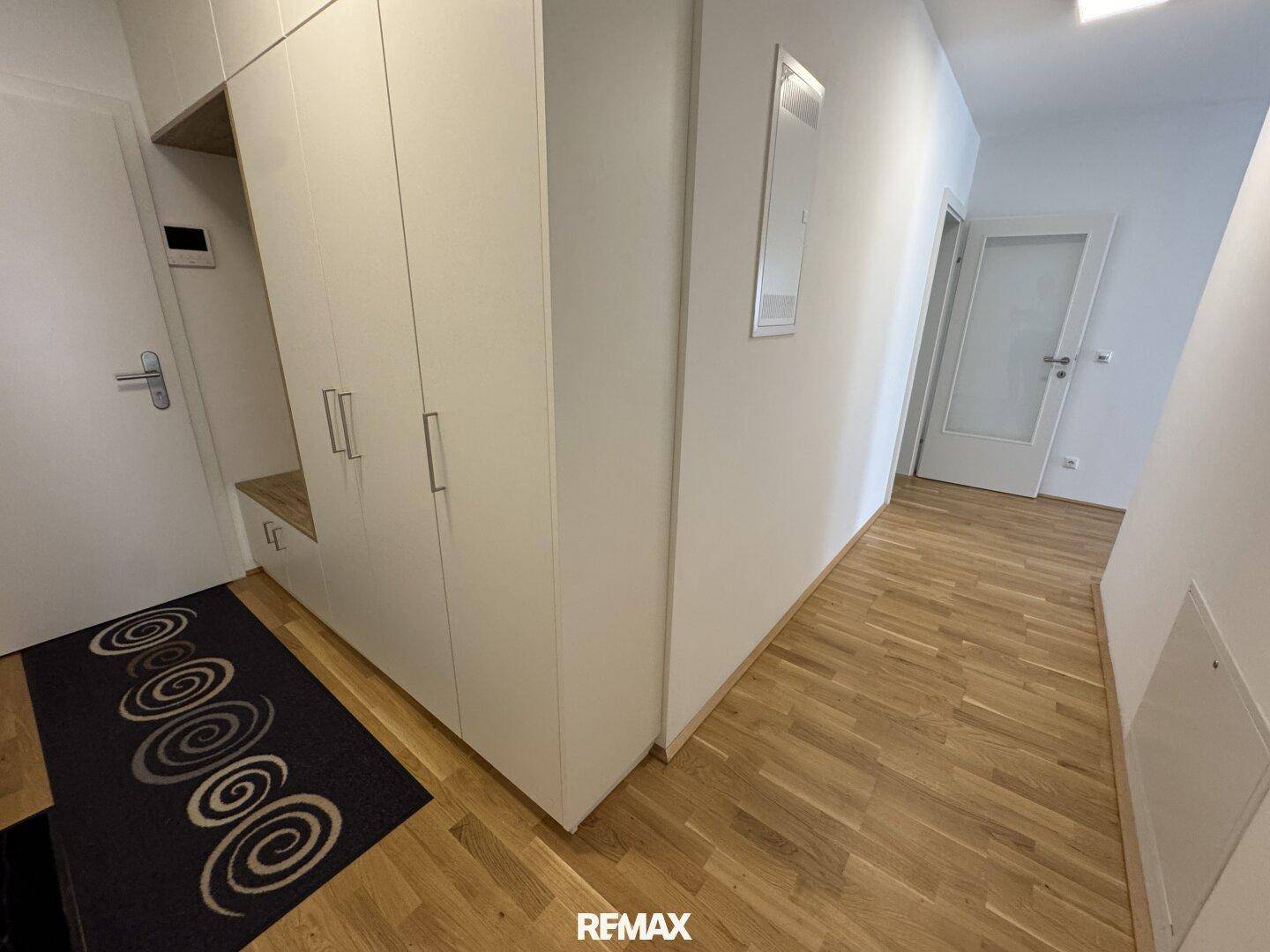 Heller Flur mit Holzparkettboden und praktischen Einbauschränken.