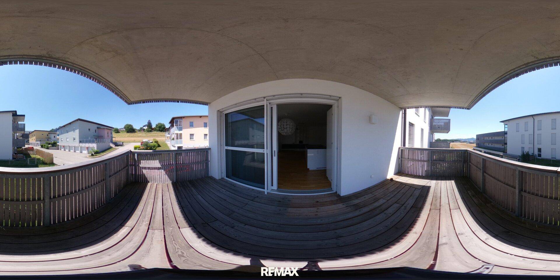 Panoramaansicht eines Balkons mit Holzboden und weitem Blick auf die Umgebung.