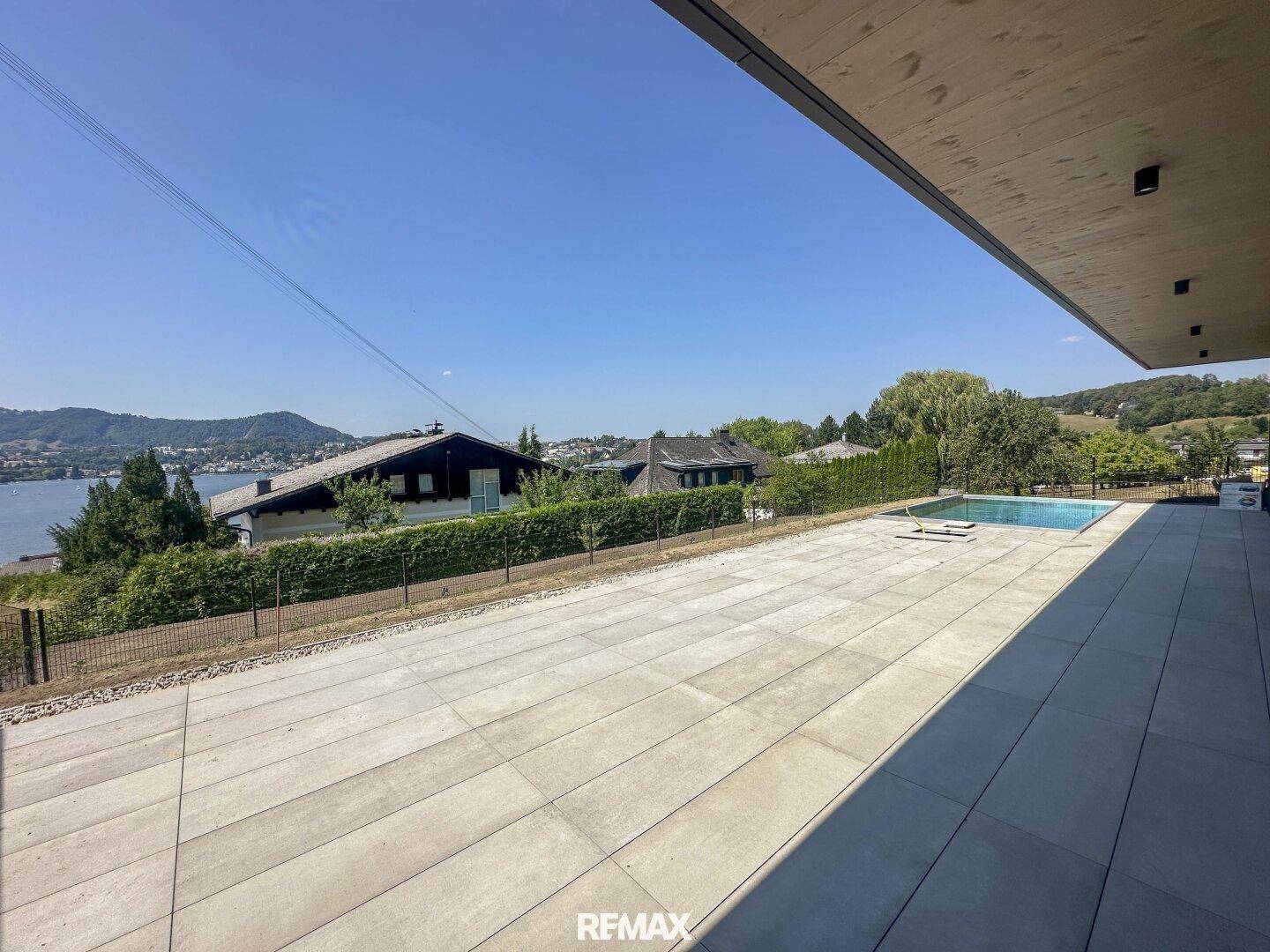 Weitläufige Terrasse mit Infinity-Pool und Panoramablick auf den See und die grüne Umgebung.