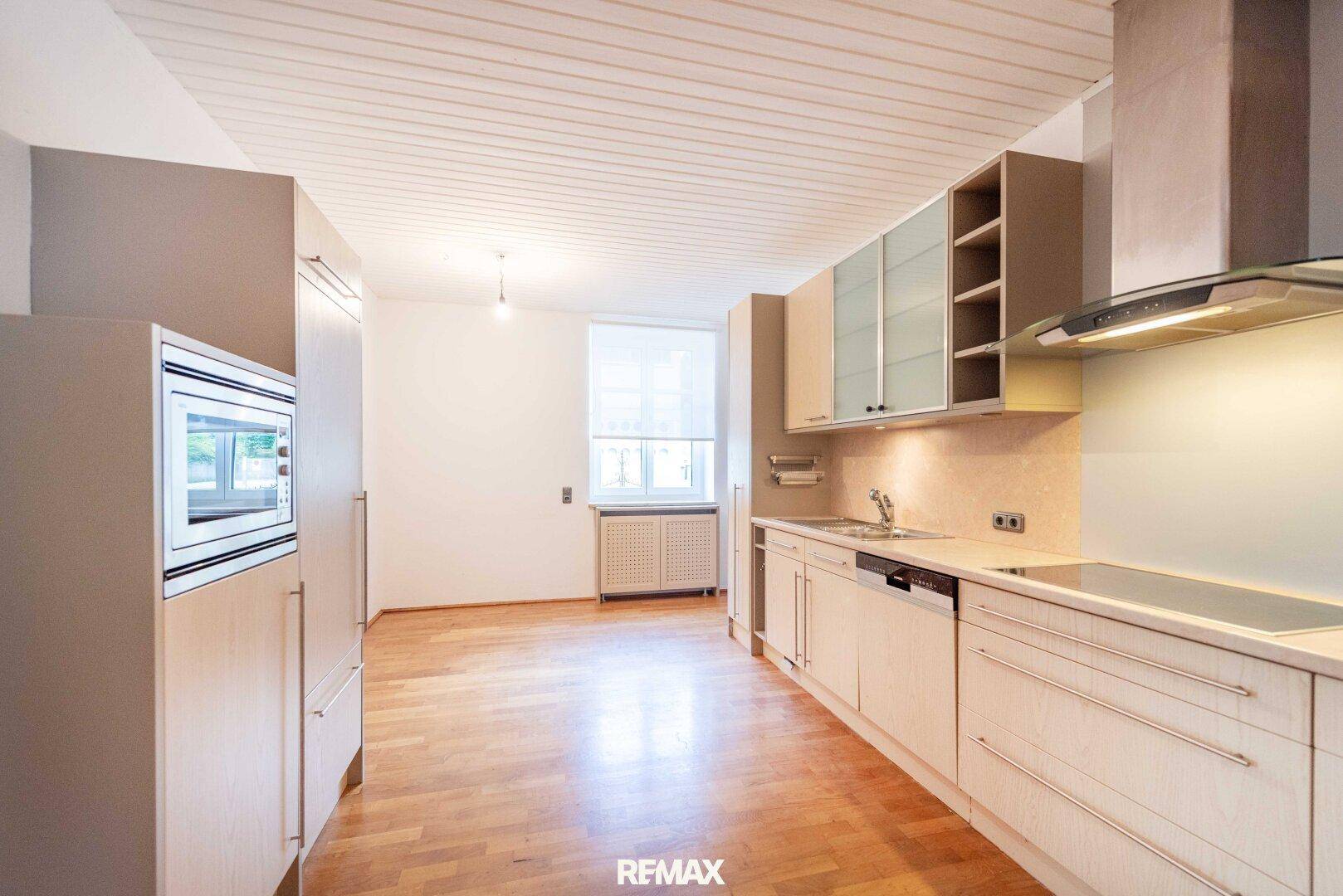 Funktionale Küche mit hellen Einbauschränken, integrierten Geräten und Holzdeckenverkleidung.