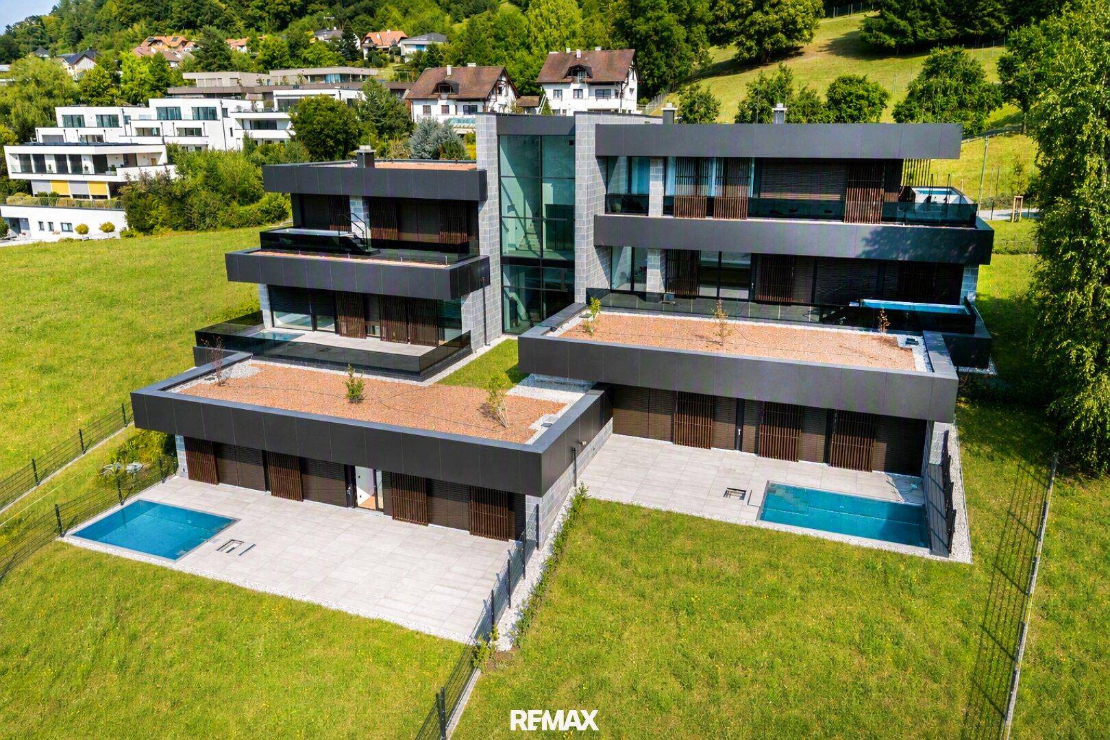 Moderne Architektur mit mehreren Wohneinheiten, Flachdächern und privaten Pools in grüner Umgebung.