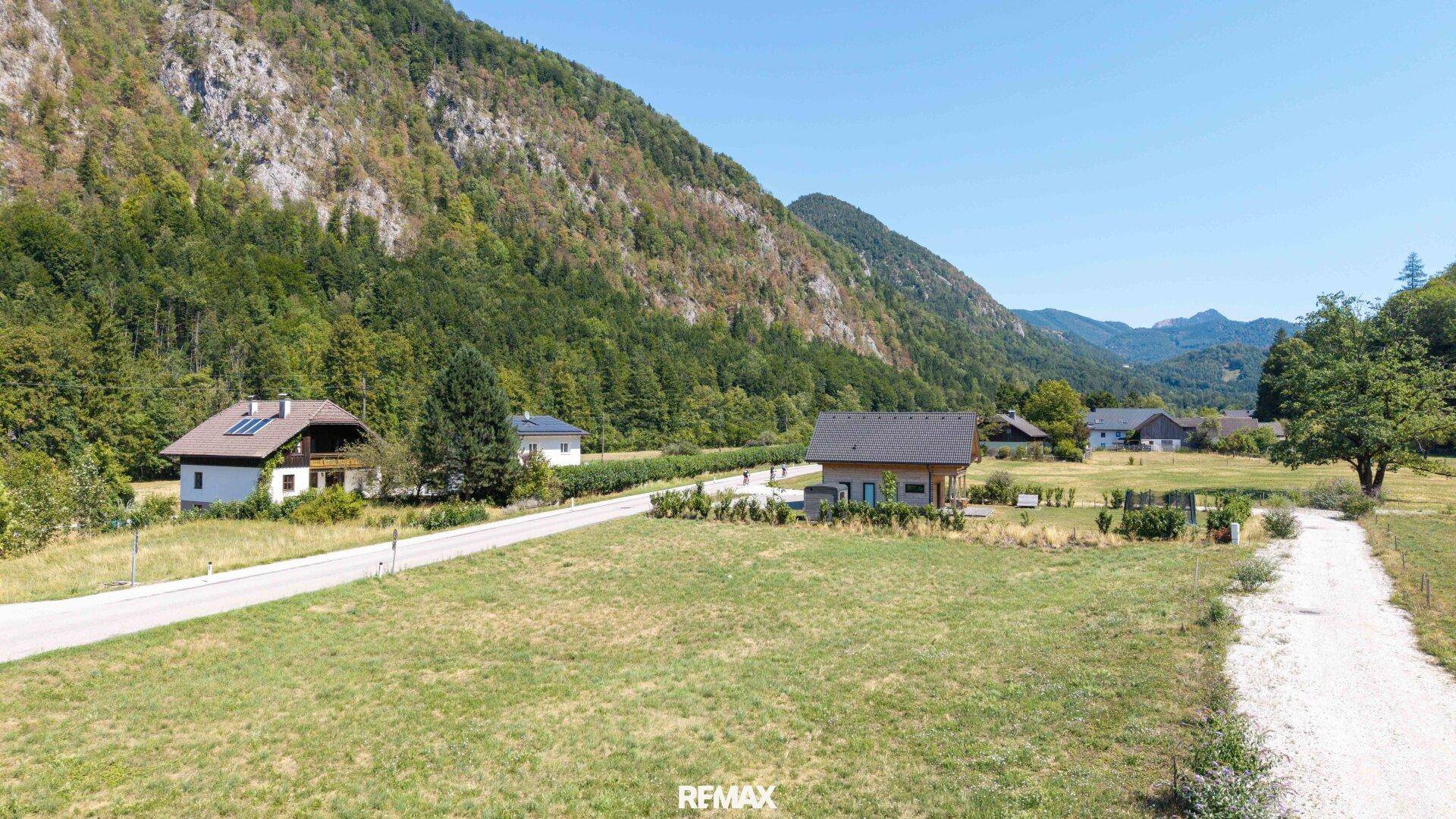 Weitläufiges Grundstück mit Straße, umgeben von Häusern und einer beeindruckenden Bergkulisse.