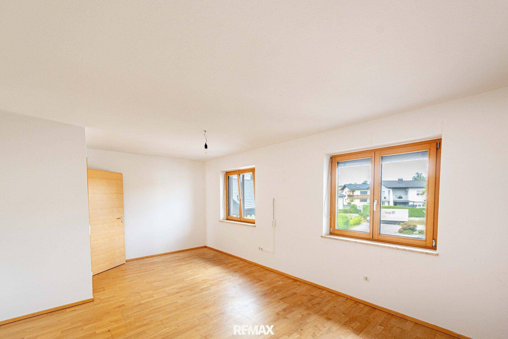 Geräumiges Zimmer mit Holzboden und zwei Fenstern, ideal als Schlaf- oder Arbeitszimmer.