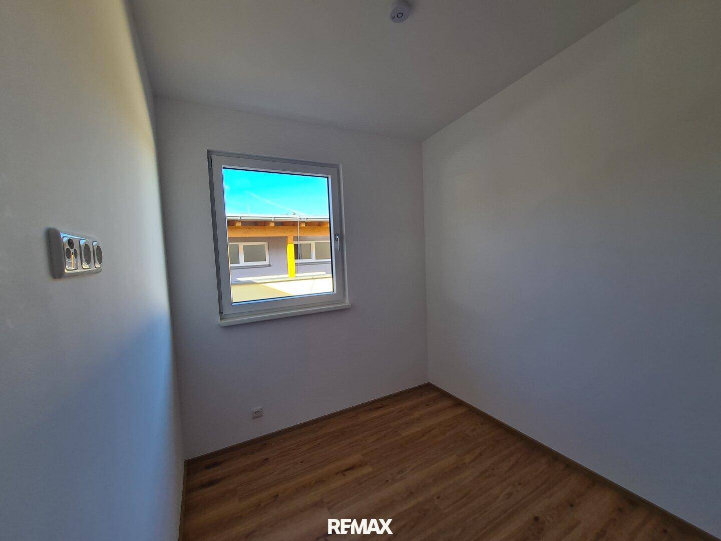 Kleiner, heller Raum mit Laminatboden und einem Fenster, ideal für ein Kinder- oder Arbeitszimmer.