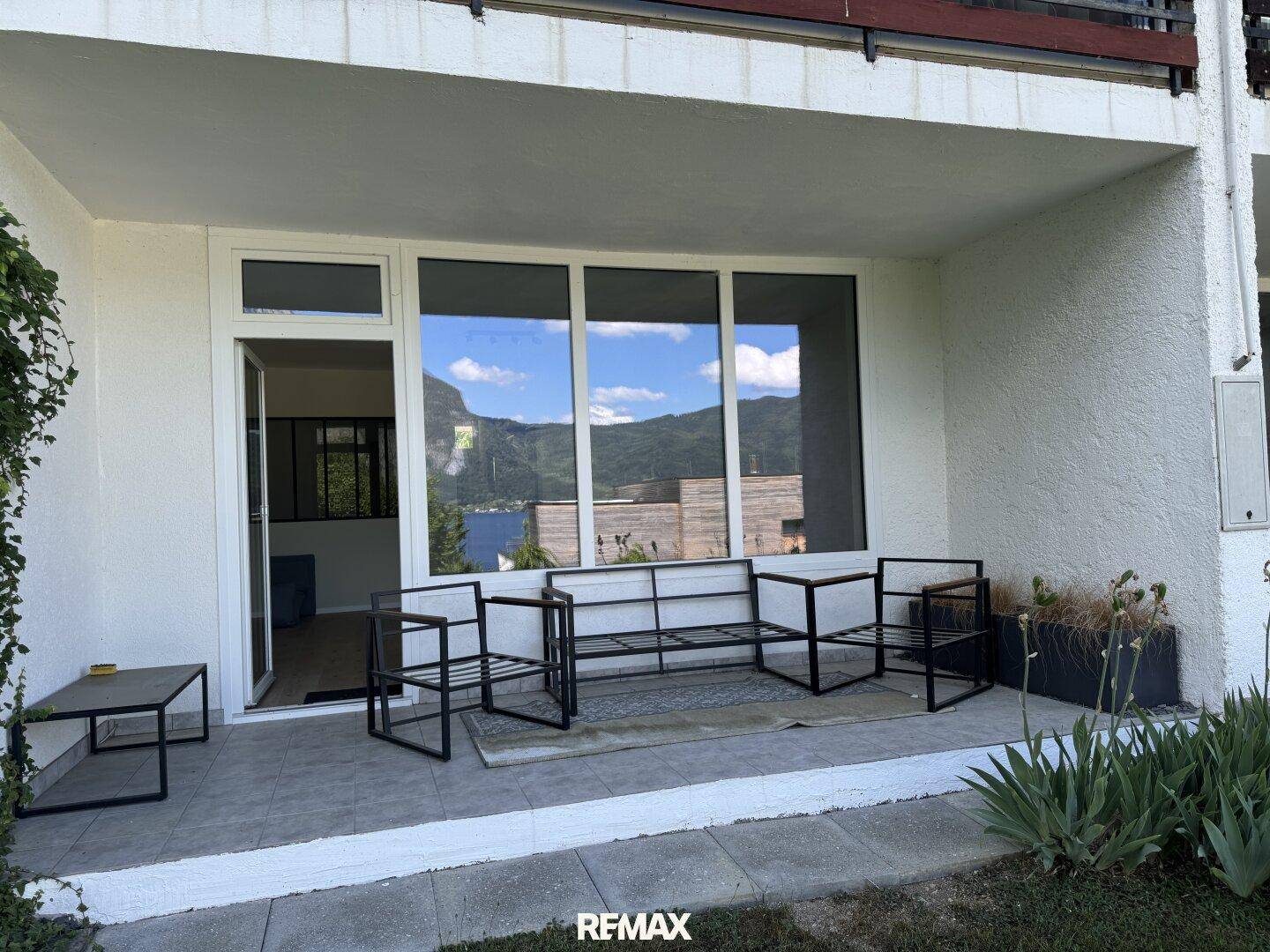 Moderne Terrasse mit Sitzgelegenheiten und weitem Blick auf den See und die Berge.