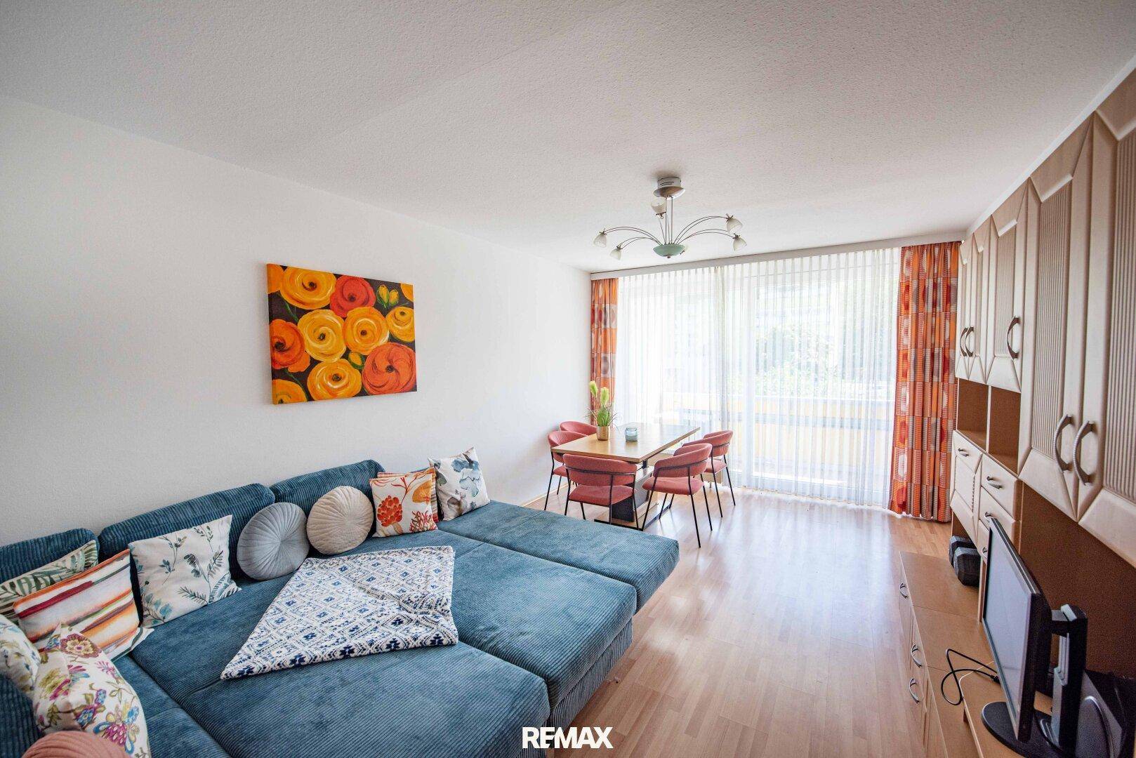Gemütlicher Wohn-Essbereich mit blauem Sofa, Esstisch und hellem Holzfußboden.