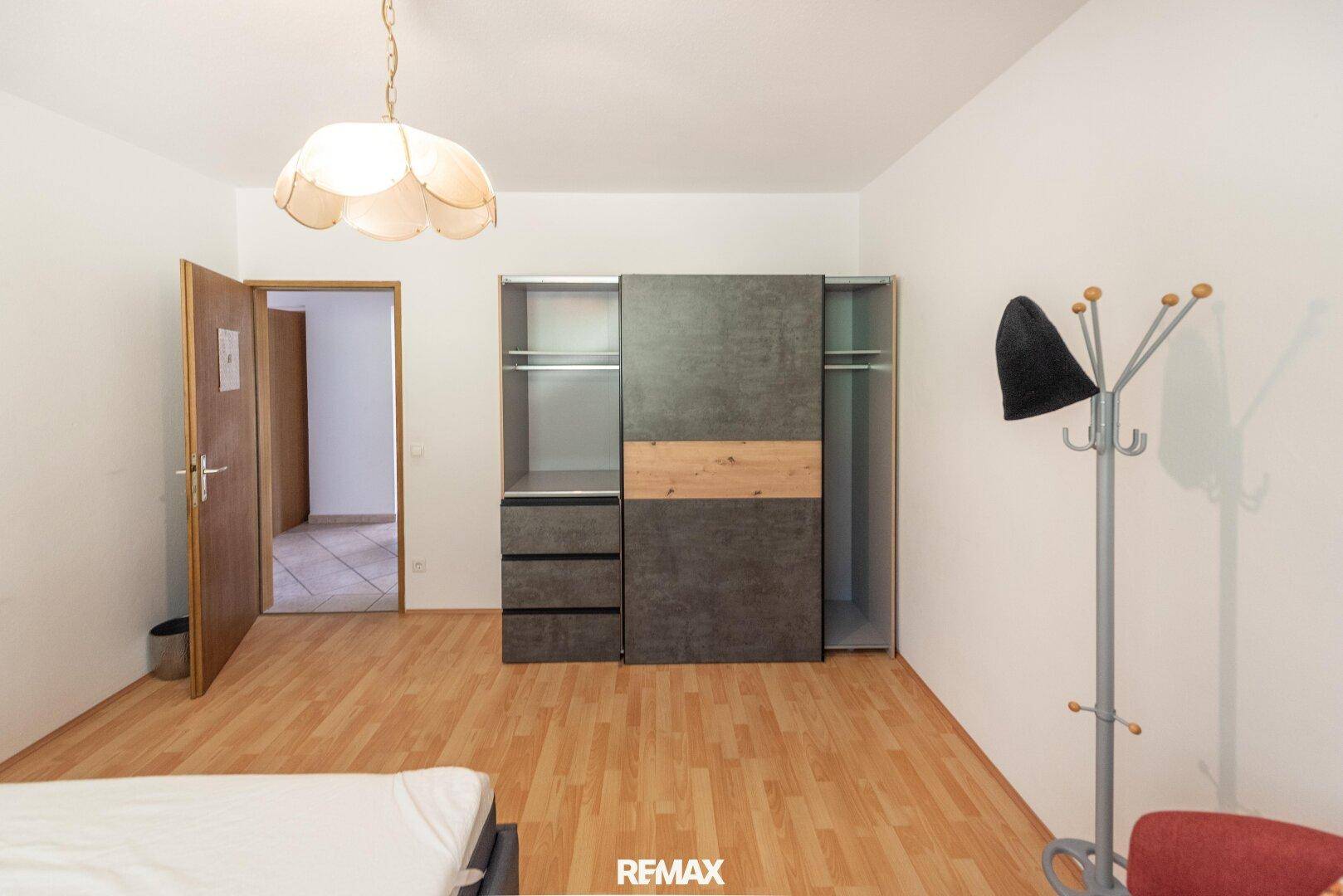 Schlafzimmer mit Schiebetürenschrank, Holzfußboden und Zugang zum Flur.