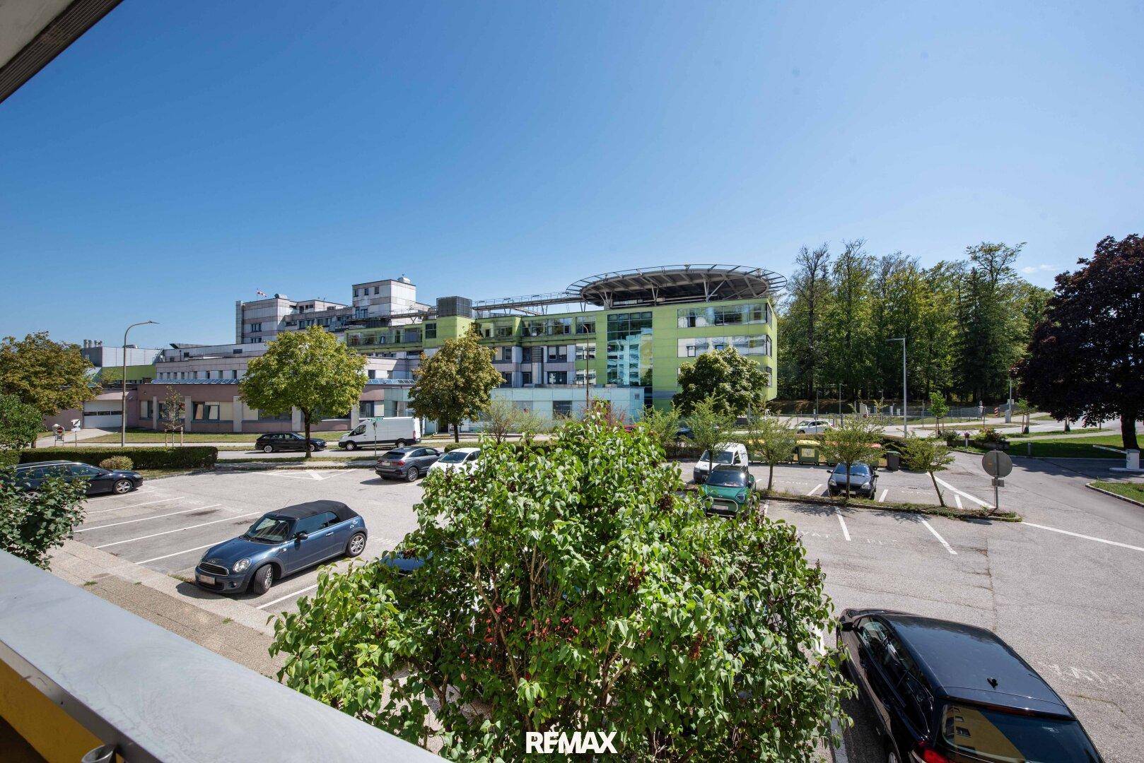 Weitblick von der Wohnung auf eine städtische Umgebung mit Parkplätzen und Gebäuden.