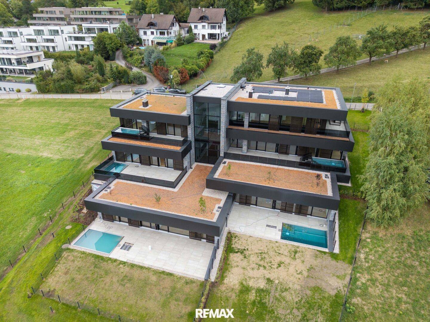 Moderne Wohnanlage mit mehreren Einheiten, Flachdächern und privaten Pools in grüner Umgebung.