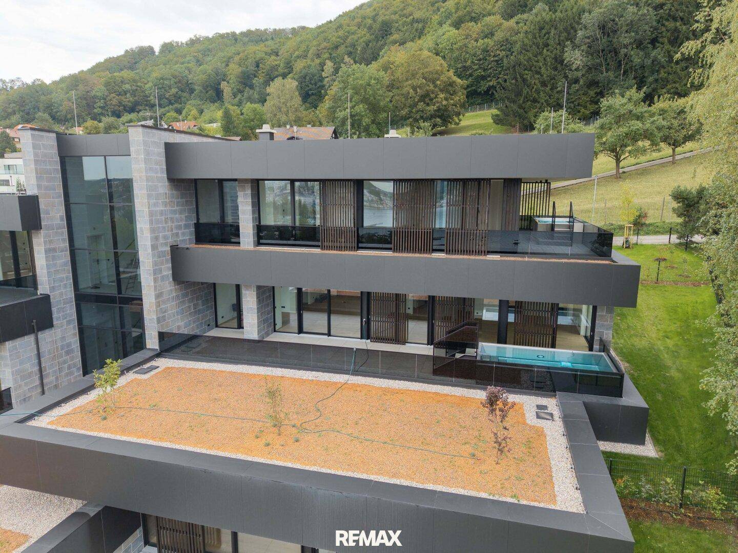 Architektonisch anspruchsvolles Gebäude mit großen Glasflächen, Balkonen und einem kleinen Pool auf der Terrasse.