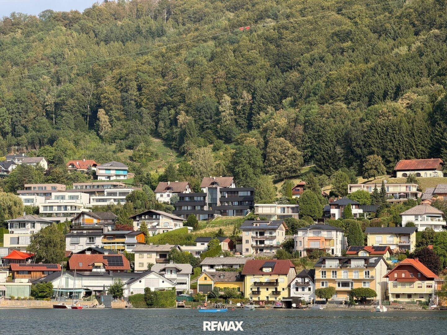 Panoramablick auf die malerische Uferbebauung und die bewaldeten Hügel am See.