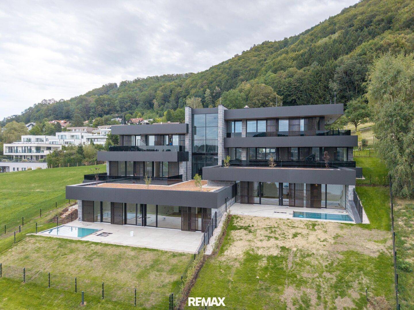 Moderne Architektur mit mehreren Terrassen, Pools und beeindruckender Hanglage am Waldrand.