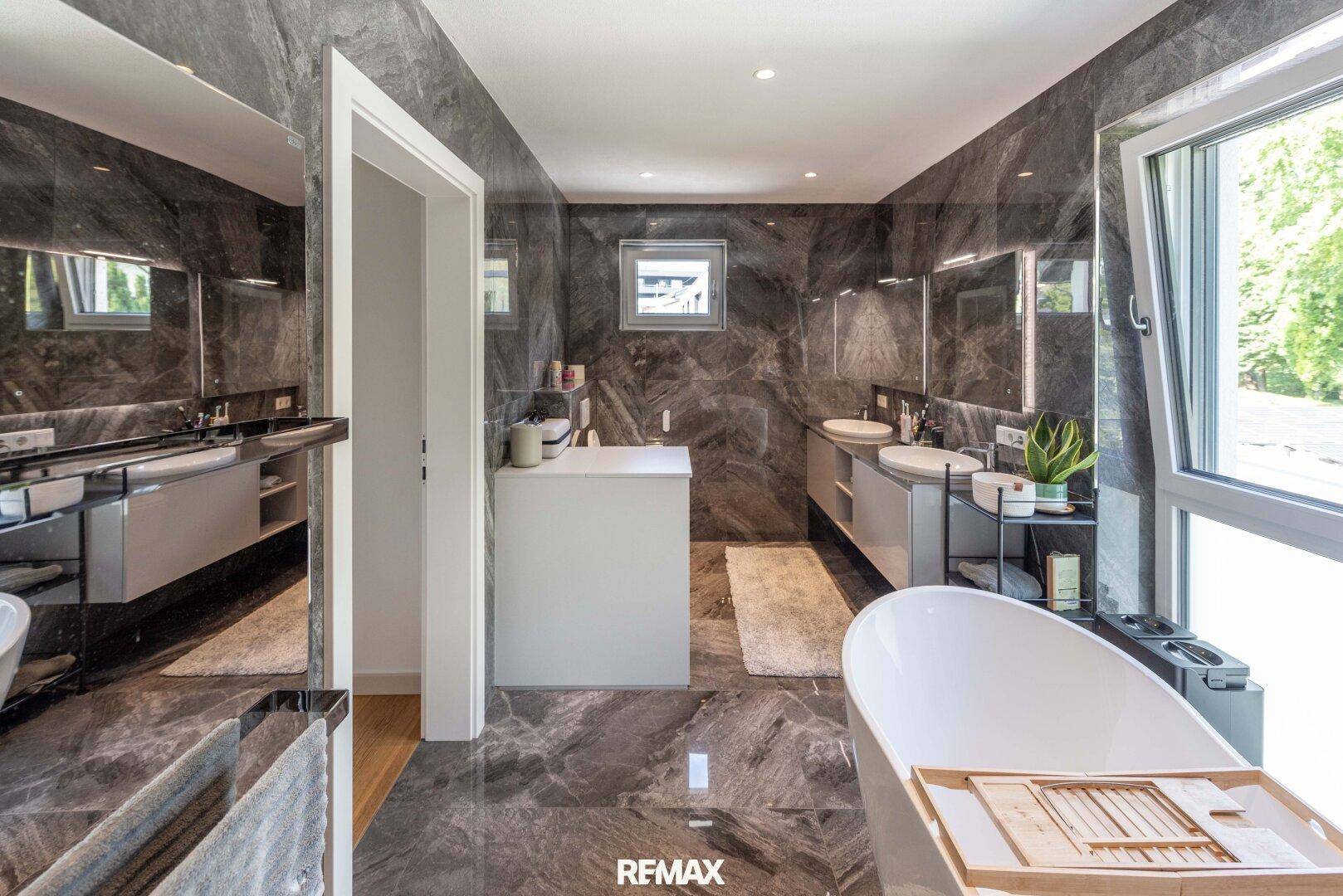 Luxuriöses Badezimmer mit freistehender Badewanne, Doppelwaschbecken und Marmorfliesen.