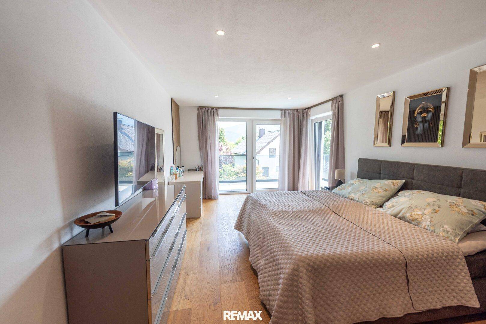 Geräumiges Schlafzimmer mit Holzboden, großen Fenstern und stilvoller Dekoration.