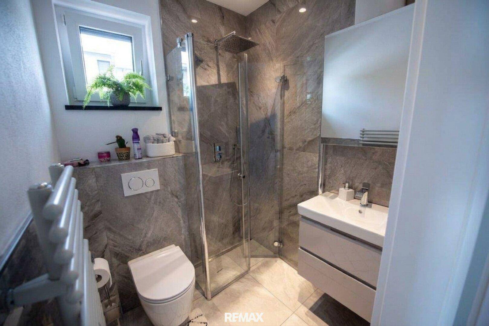 Modernes Badezimmer mit ebenerdiger Dusche, Wand-WC und beheiztem Handtuchhalter.