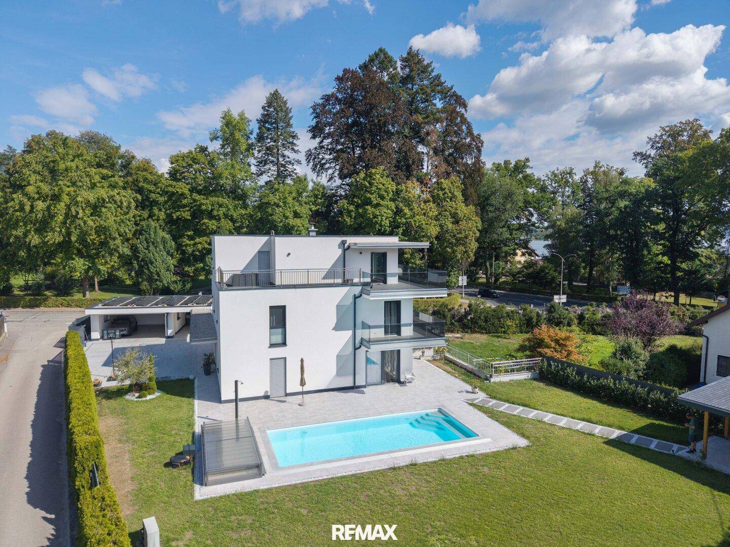 Luftaufnahme der modernen Villa mit Pool, Carport und weitläufigem Gartenbereich.