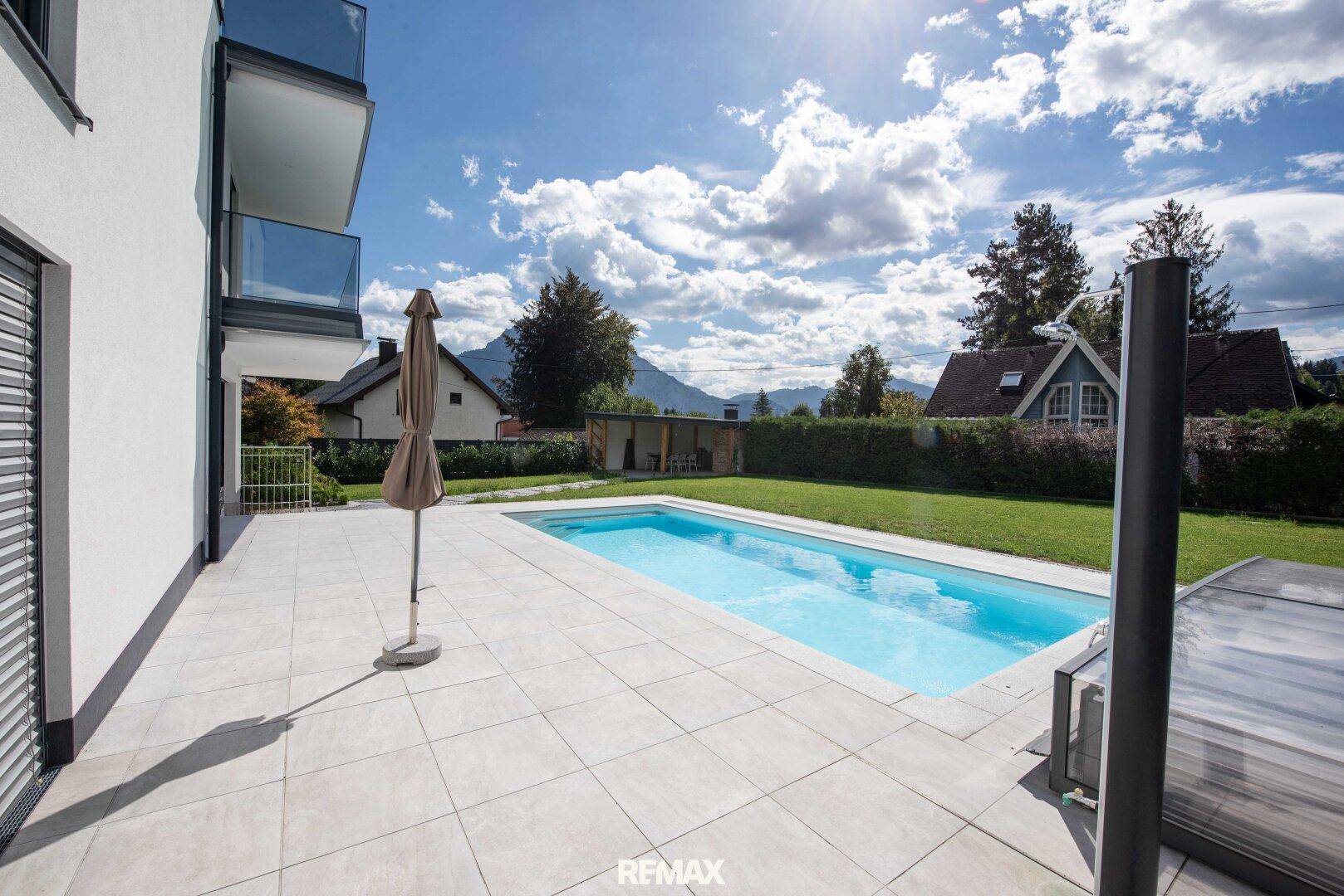 Sonniger Terrassenbereich mit privatem Pool und Liegefläche, umgeben von Grün.