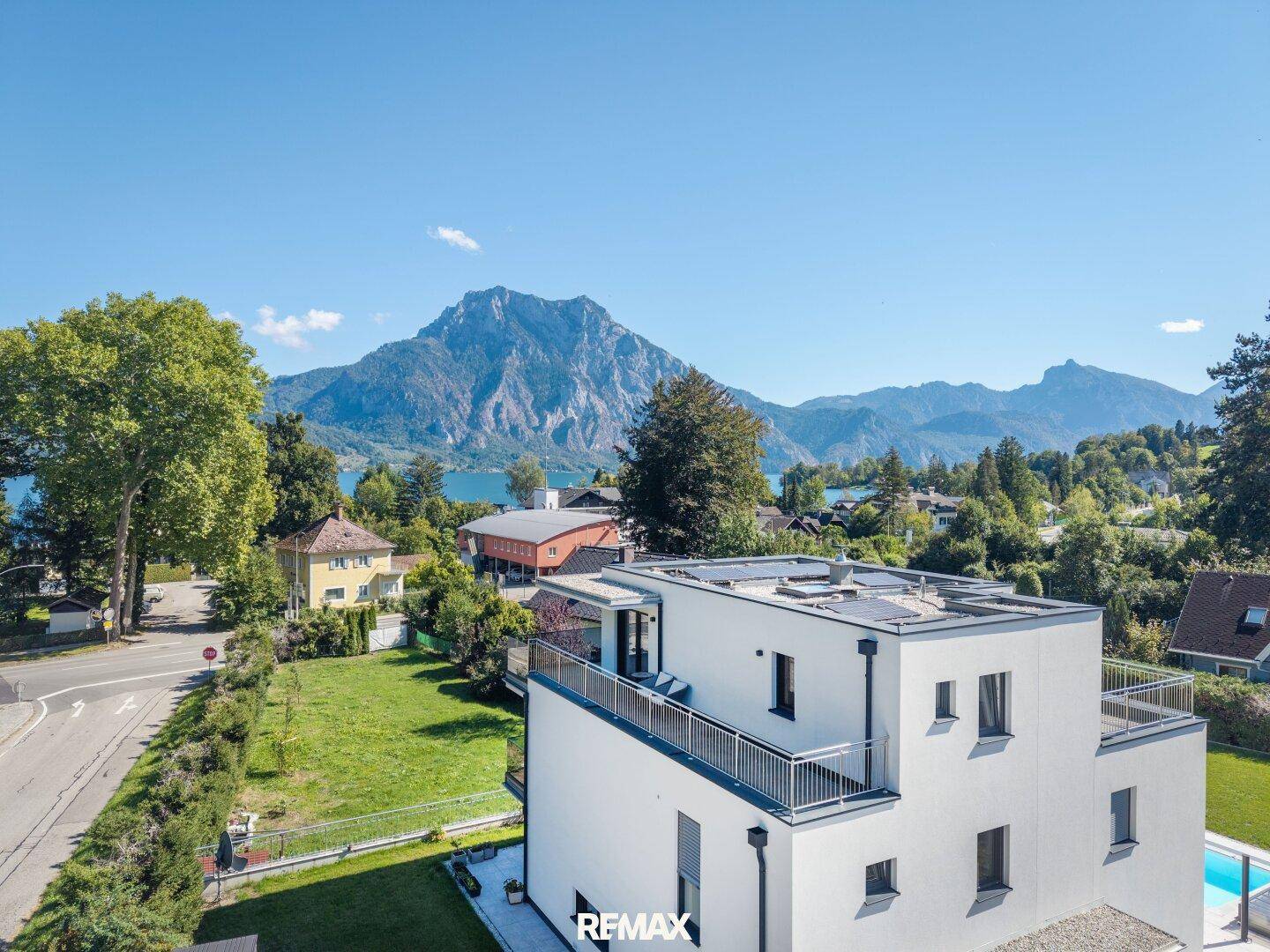 Moderne Architektur mit Flachdach und Dachterrasse, umgeben von Natur und Bergblick.