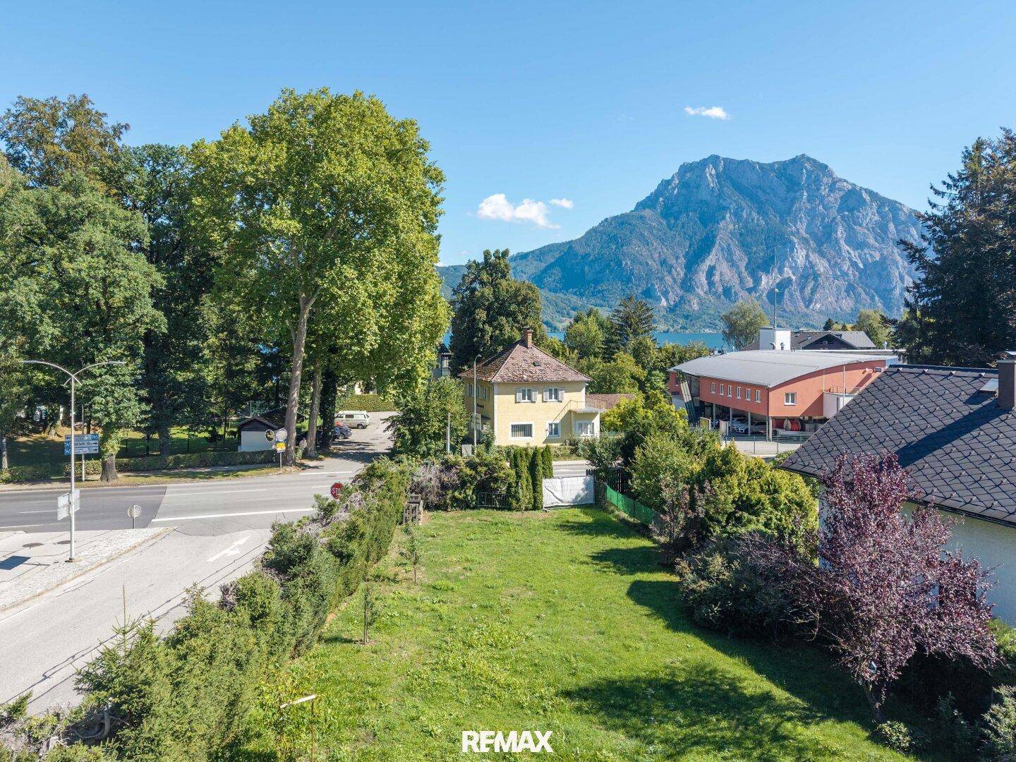 Weitläufige Grünfläche mit Blick auf den See und die umliegende Berglandschaft.
