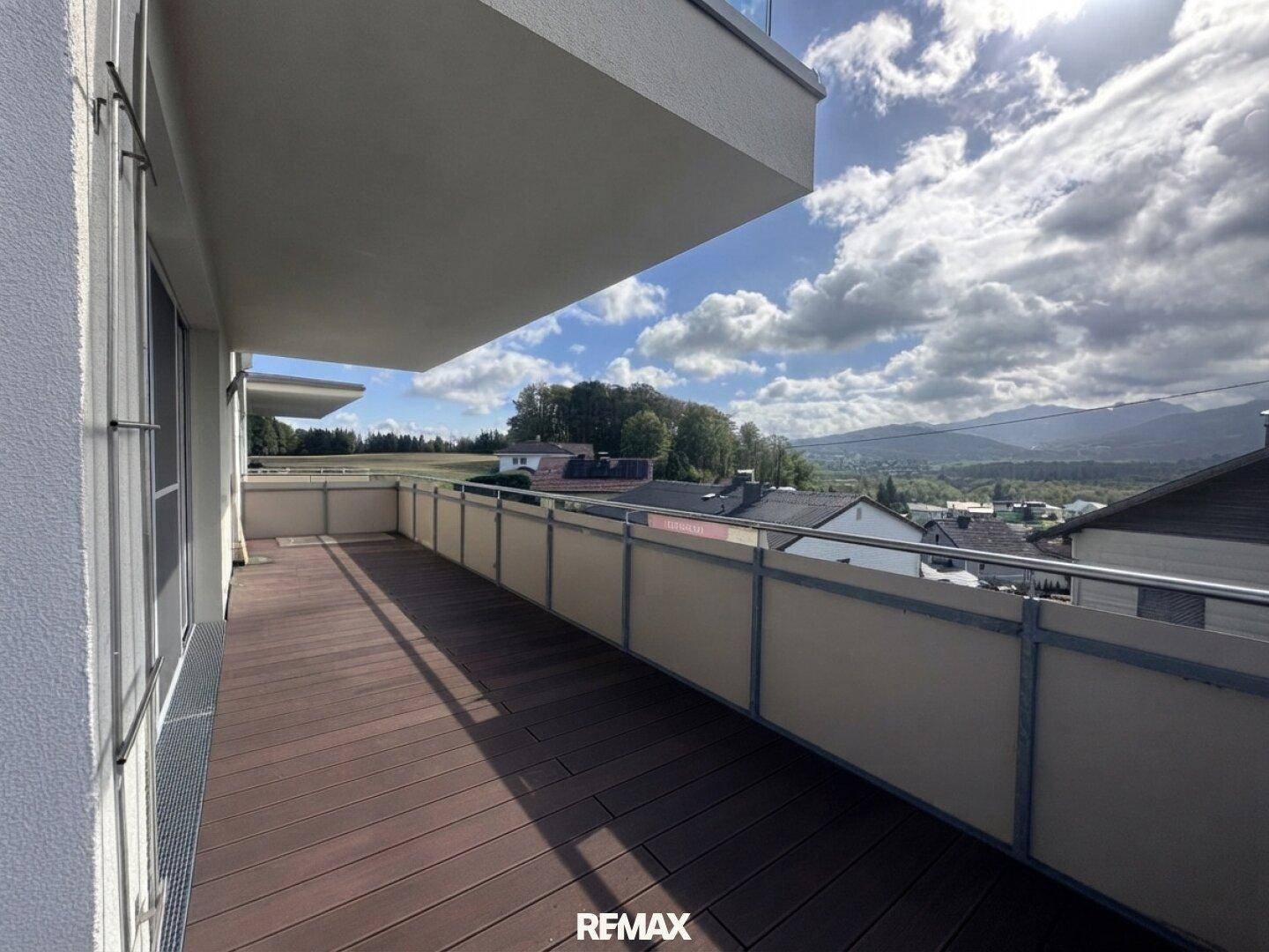 Langer Balkon mit Holzdielenboden und Metallgeländer, bietet einen weiten Blick auf die umliegende Landschaft.