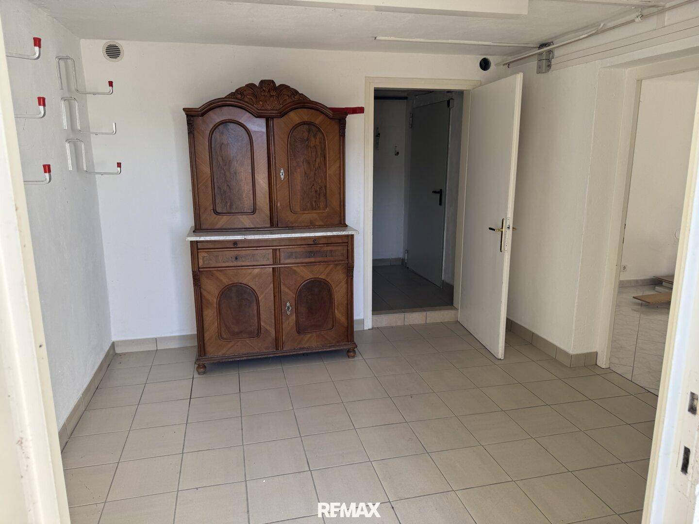 Flur mit Fliesenboden und einem antiken Holzschrank, der Stauraum bietet.