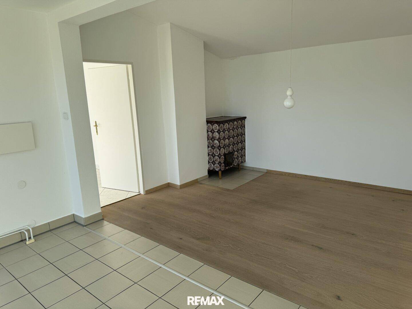 Wohnbereich mit Holzboden und einem traditionellen Kachelofen, der Wärme und Gemütlichkeit spendet.