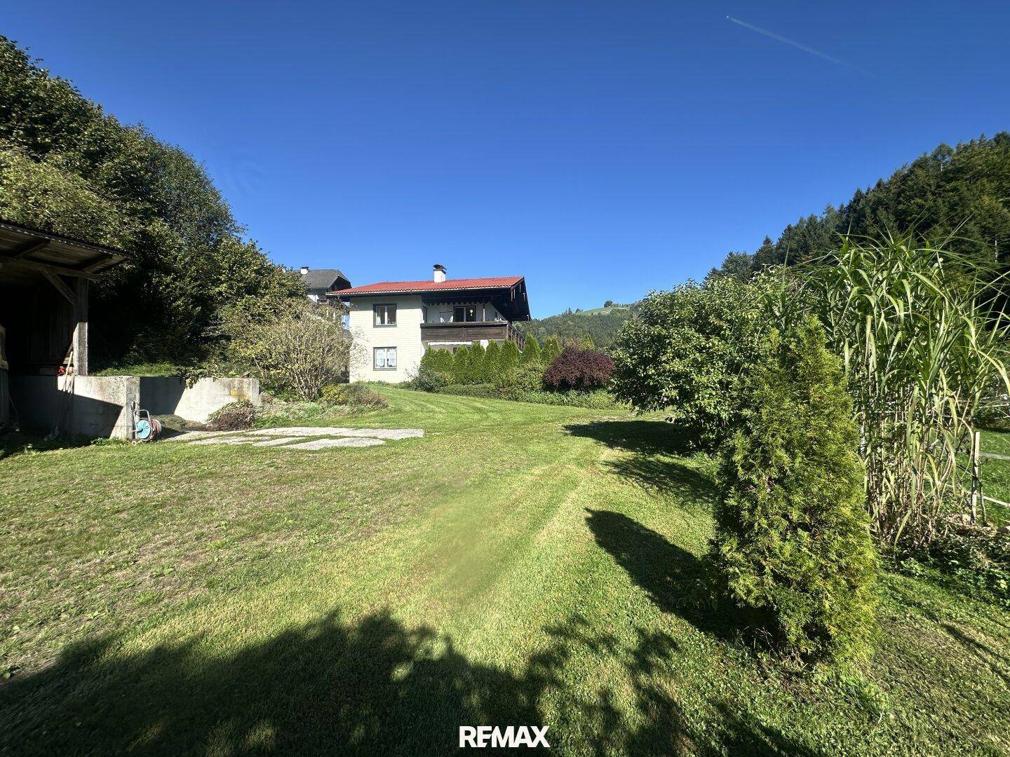 Weitläufiger Gartenbereich mit gepflegtem Rasen und Blick auf das Wohnhaus in grüner Umgebung.