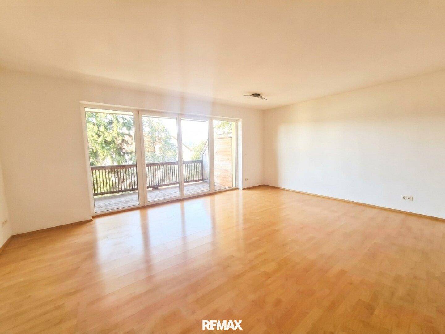 Helles Wohnzimmer mit Parkettboden und großzügigem Zugang zum Balkon, bereit zur individuellen Gestaltung.