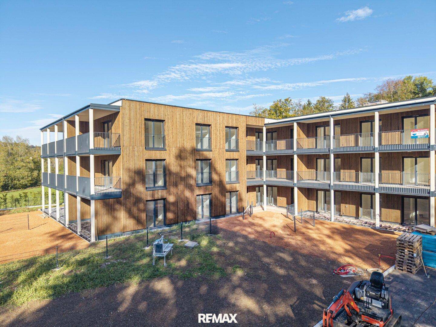 Nahaufnahme der modernen Holzfassade eines Neubaus mit zahlreichen Balkonen und großen Fenstern.