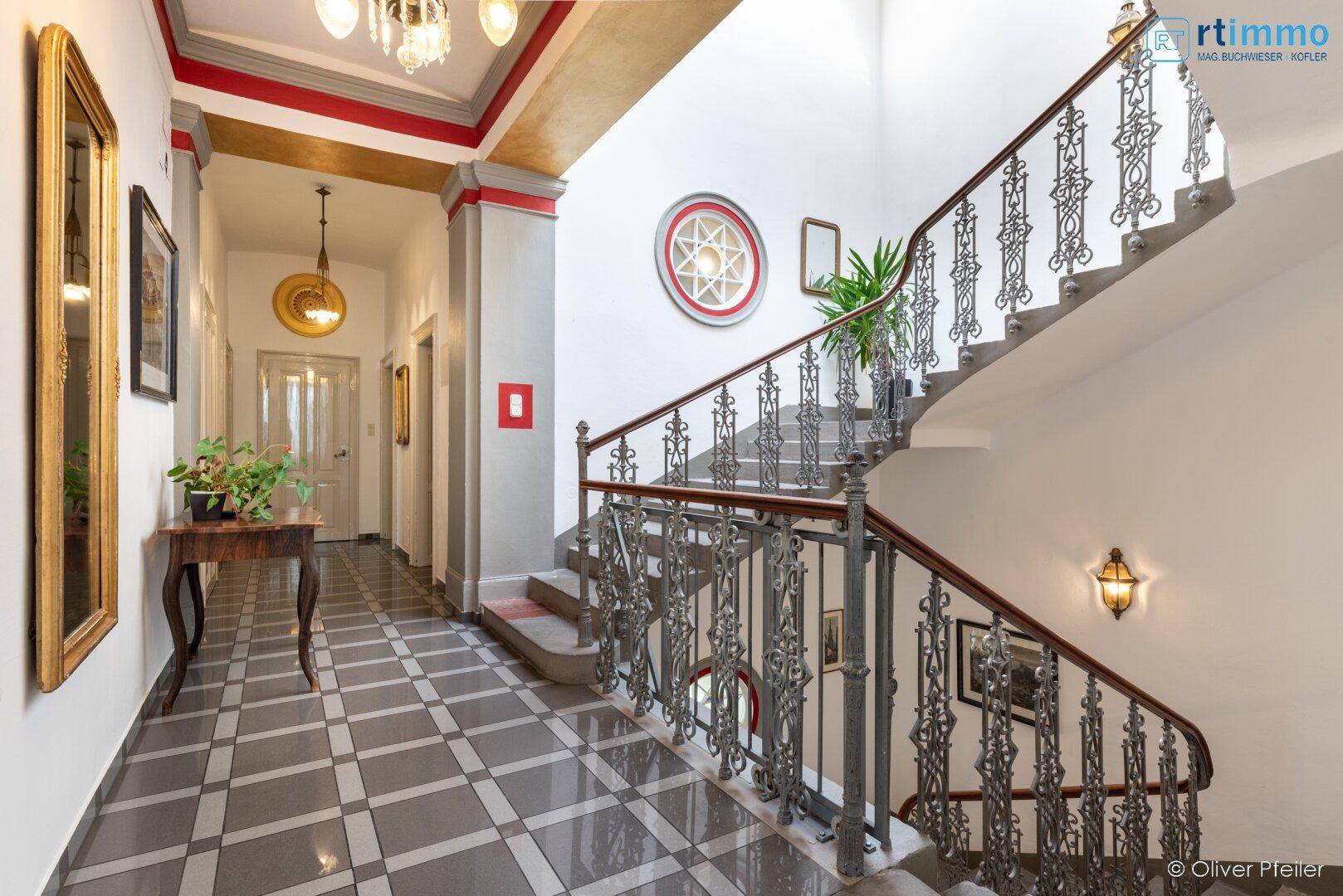 Repräsentativer Eingangsbereich mit historischer Treppe, Fliesenboden und Stuckelementen.