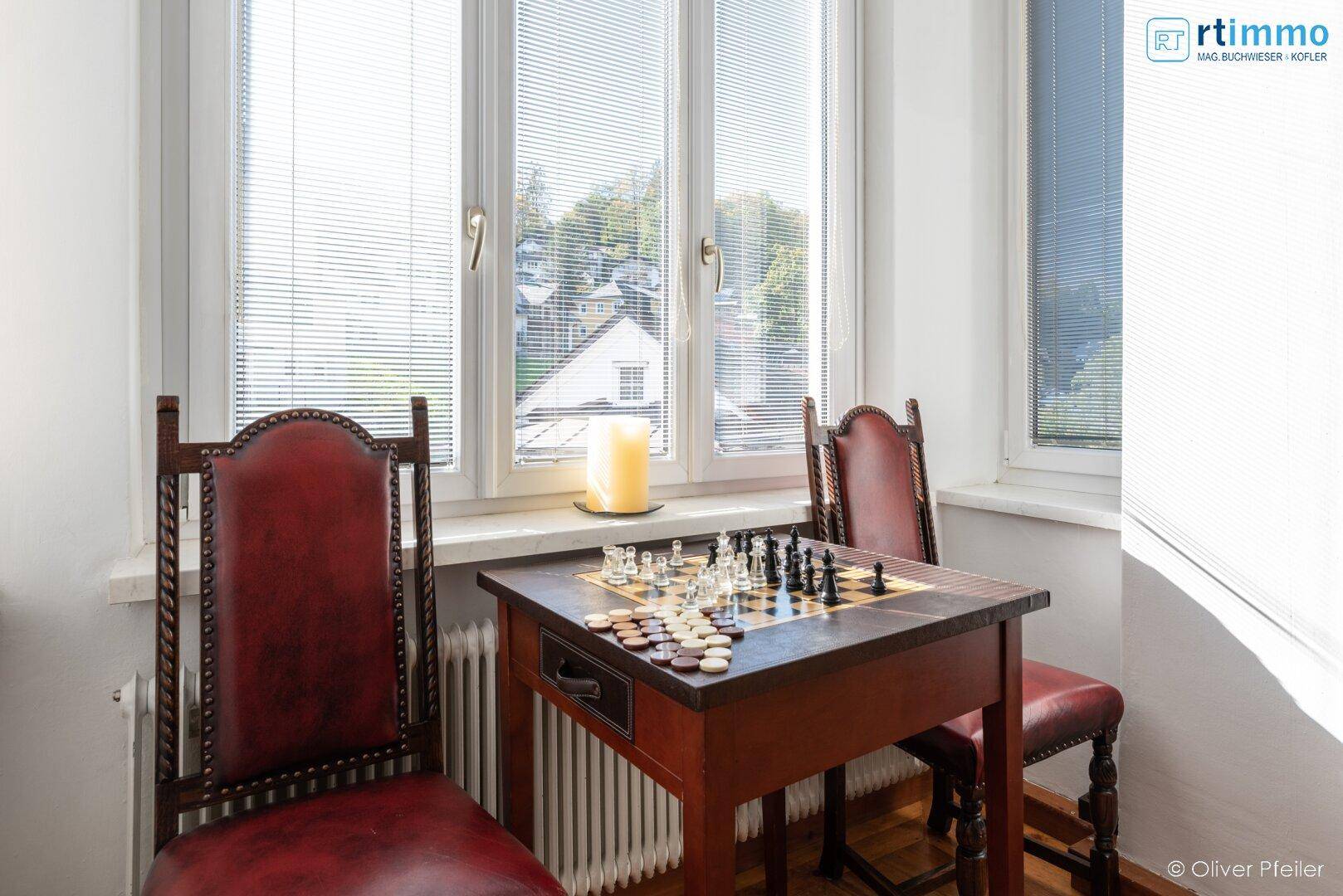 Detailansicht einer Sitzecke mit Schachspiel und Fensterblick.