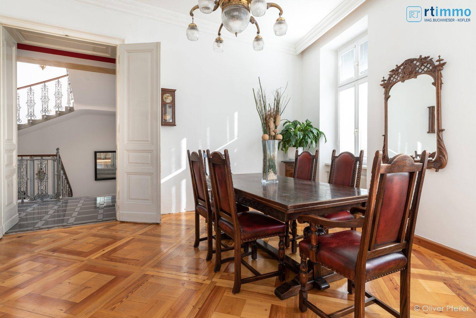 Eleganter Essbereich mit großem Holztisch, Lederstühlen und Kronleuchter.