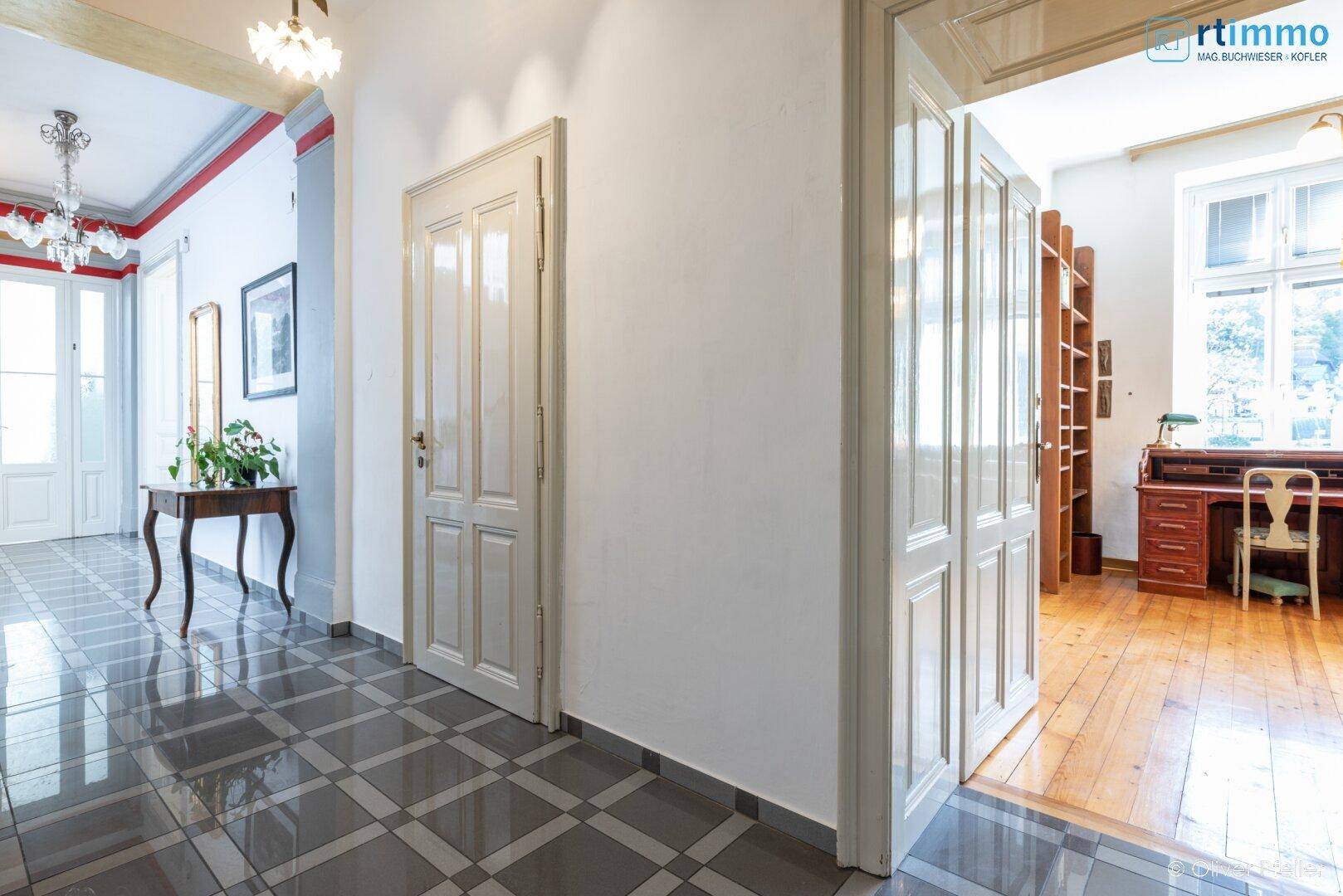 Eleganter Flur mit gemusterten Fliesen und Zugang zu einem hellen Arbeitszimmer mit Holzboden.