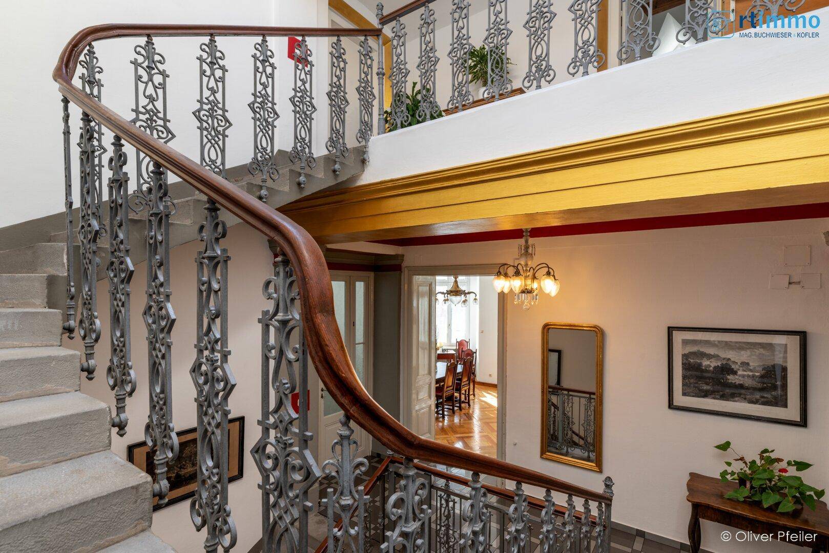 Historische Treppe mit kunstvollem Geländer und Blick in den angrenzenden Essbereich.