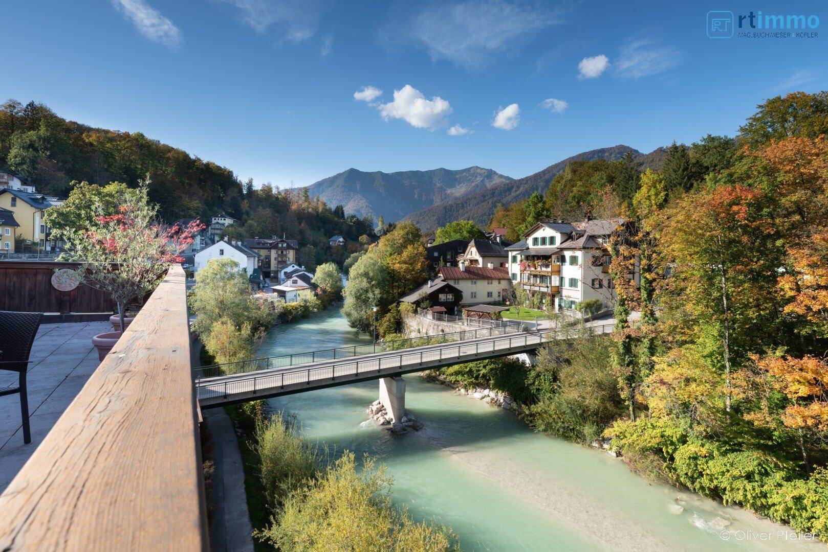 Weitläufiger Balkon mit Sitzgelegenheiten und einem idyllischen Blick auf Fluss und Berglandschaft.