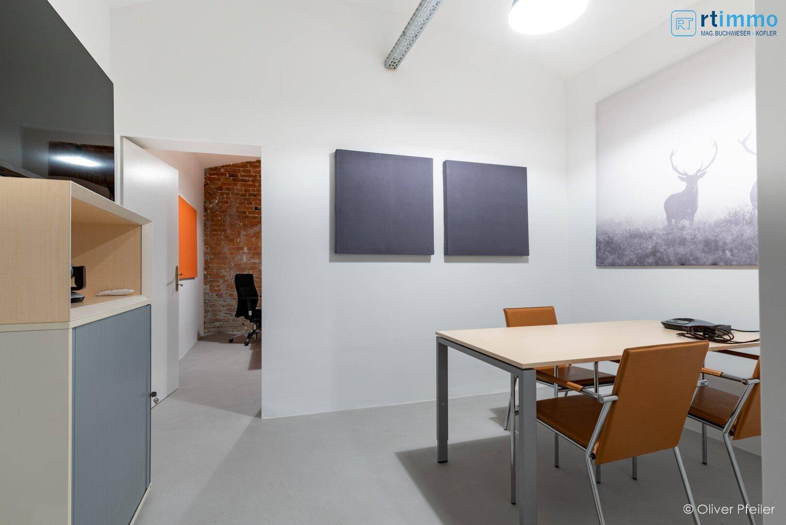 Besprechungsraum mit einem Tisch, Stühlen, Wandkunst und schallabsorbierenden Paneelen an der Wand.