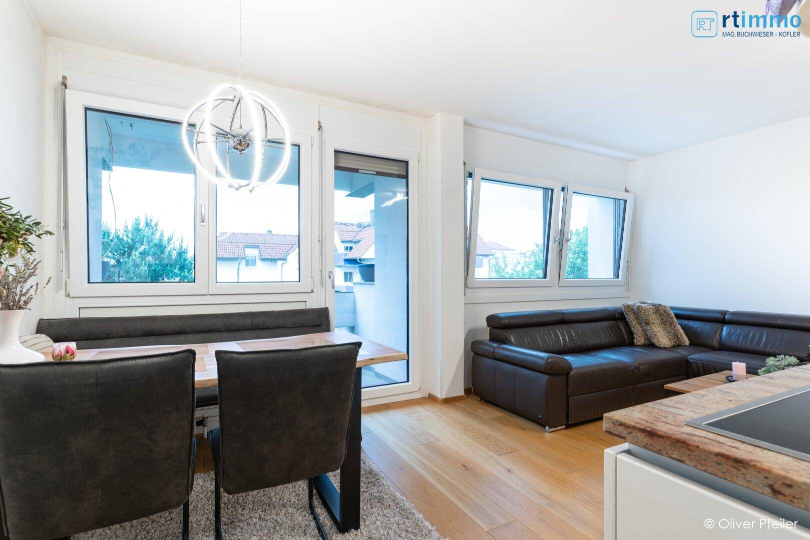Heller Essbereich mit Sitzbank und angrenzendem Wohnbereich, mit Zugang zum Balkon.