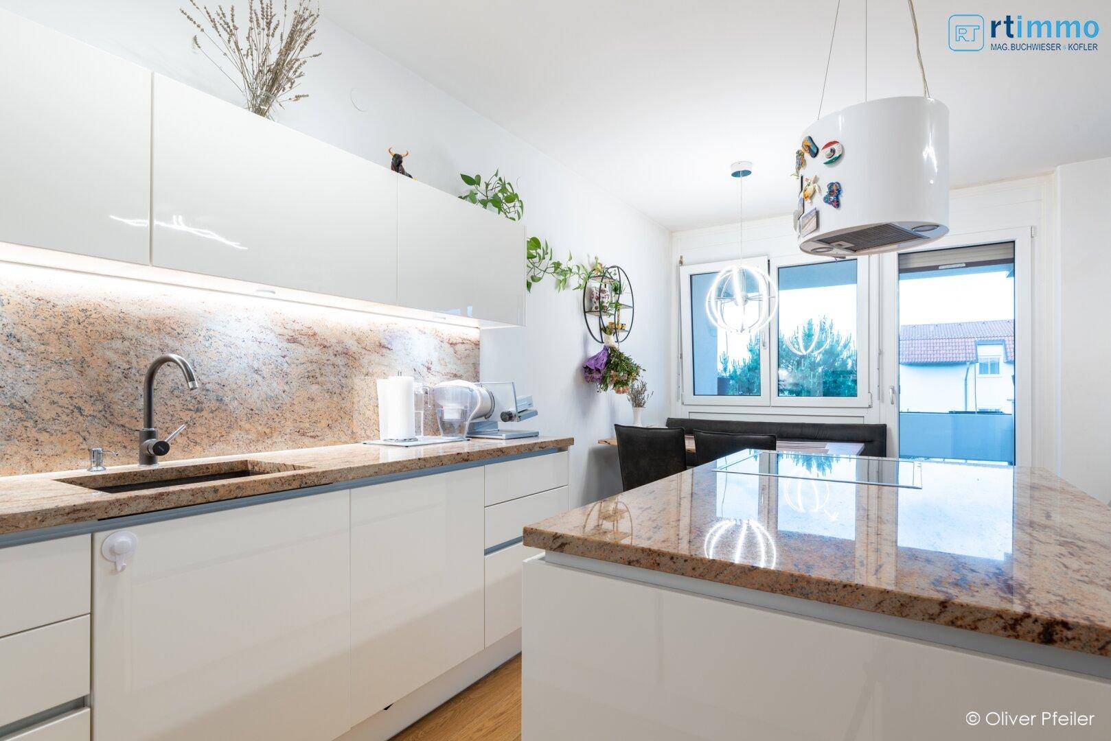 Elegante weiße Einbauküche mit Granitarbeitsplatten, integriertem Spülbecken und modernen Geräten.