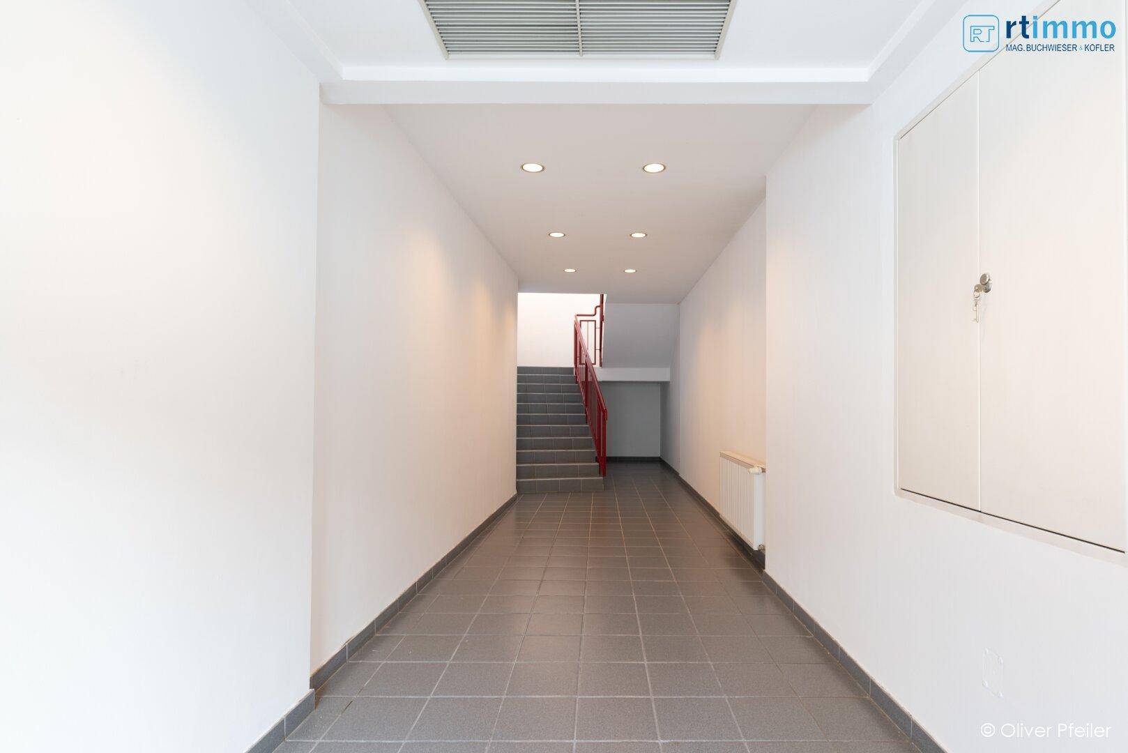 Eingangsbereich mit Fliesenboden, Deckenleuchten und Treppenaufgang.