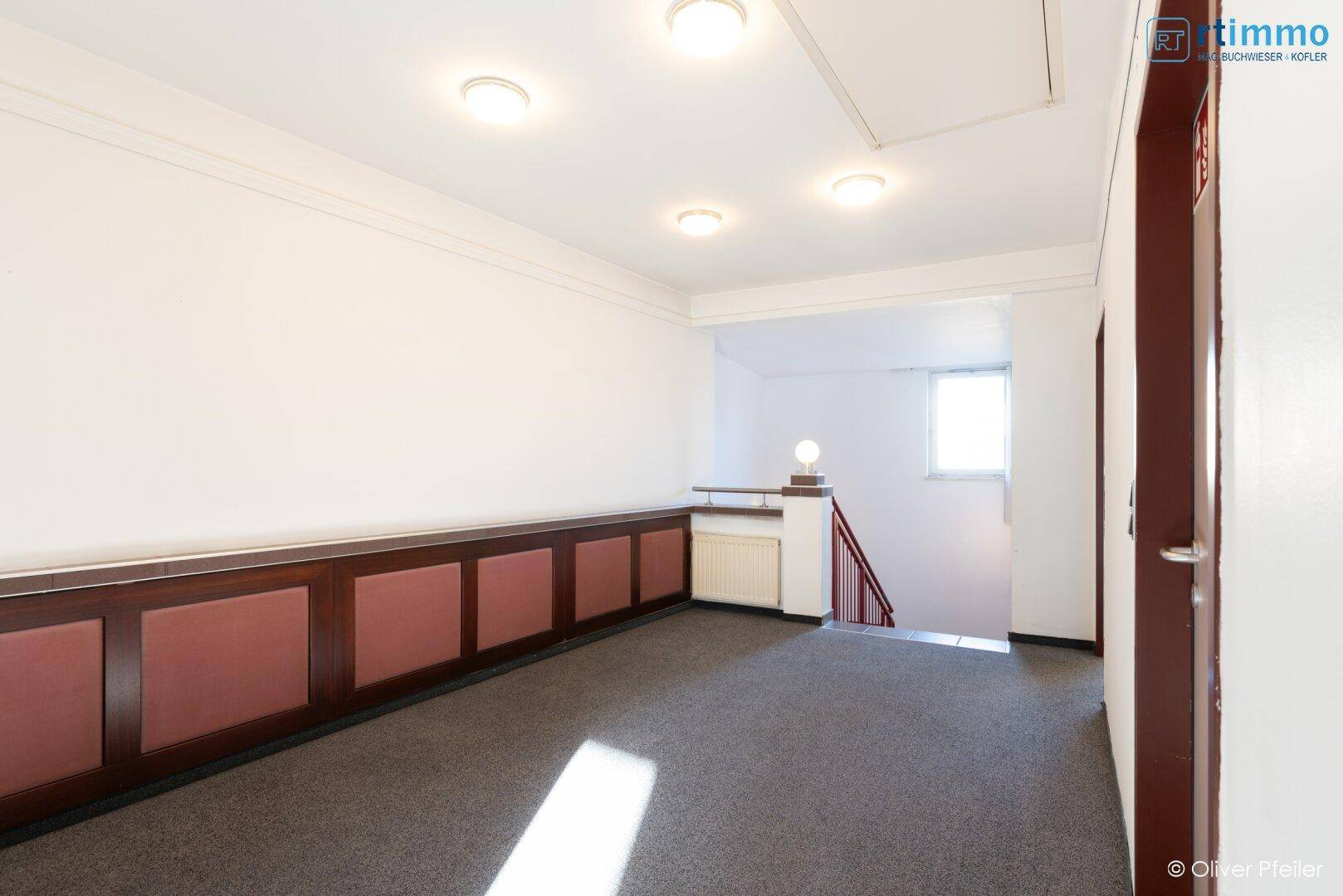 Flur mit Teppichboden, Holzvertäfelung und Zugang zum Treppenhaus.
