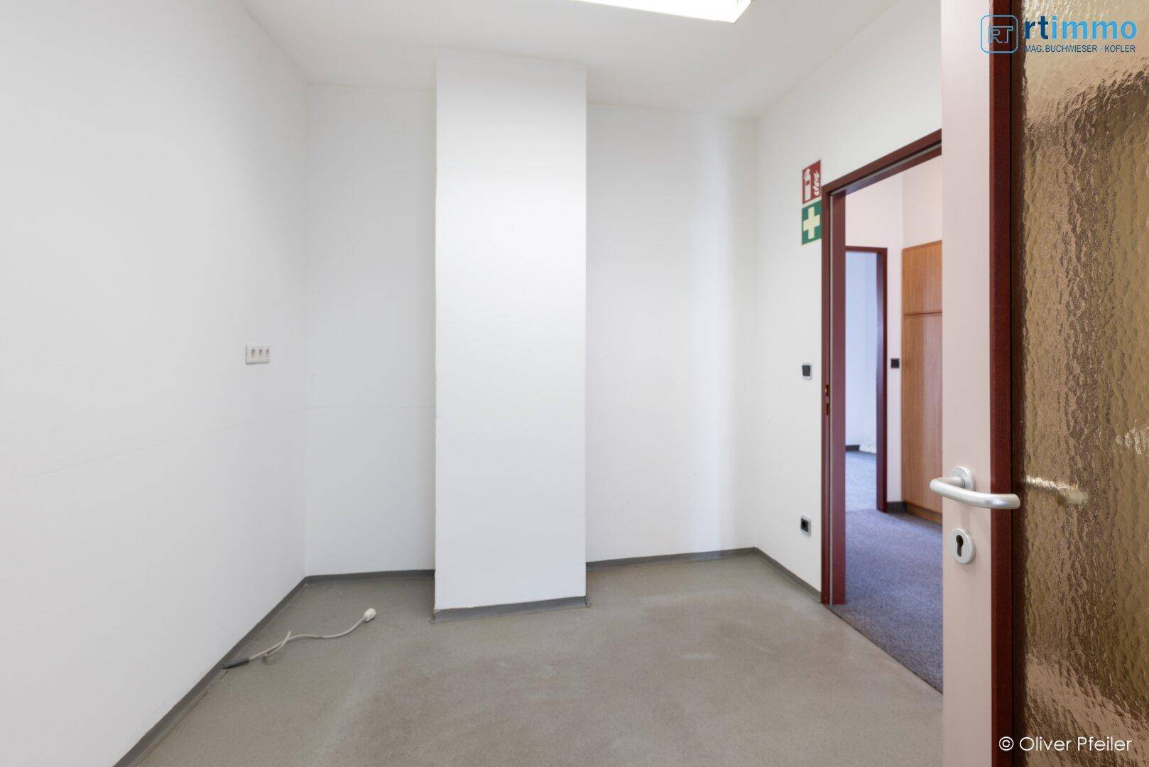 Kleiner Raum mit Betonboden und einer Tür, ideal als Abstellraum.