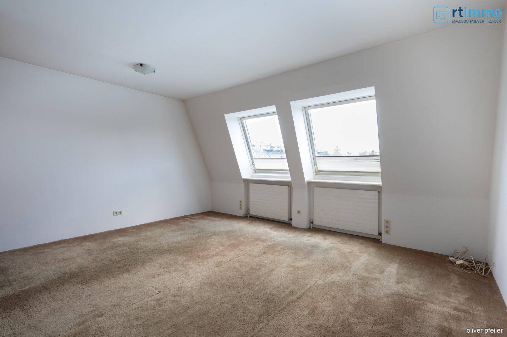 Schlafzimmer im Dachgeschoss mit Teppichboden und schrägen Dachfenstern.