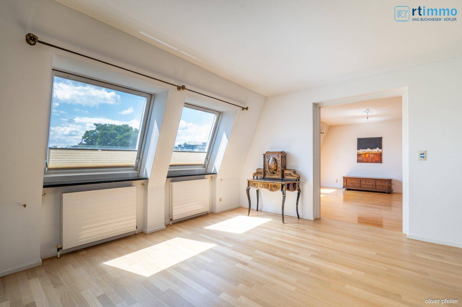 Helles Wohnzimmer im Dachgeschoss mit Parkettboden und schrägen Dachfenstern.