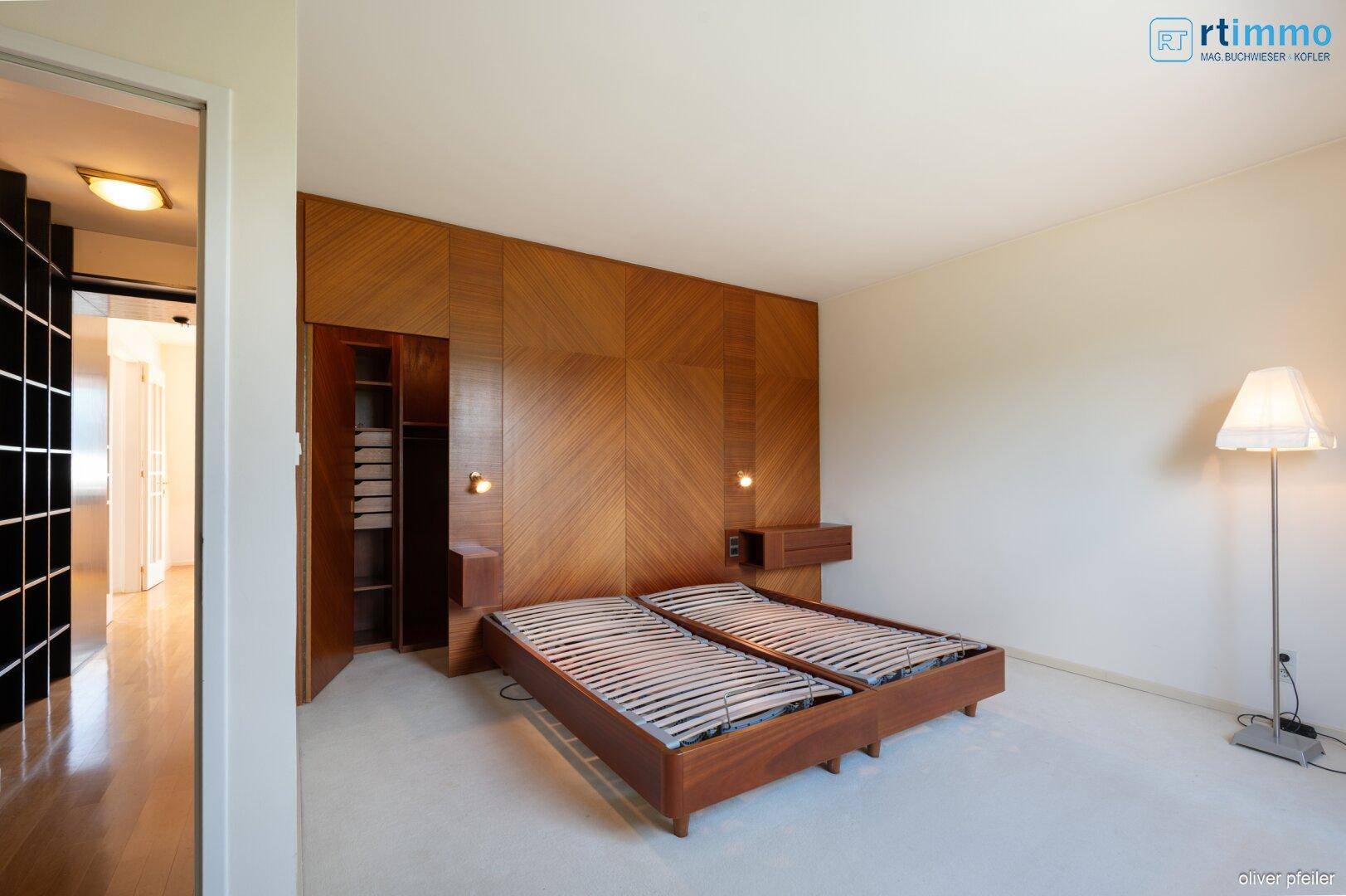 Schlafzimmer mit Holzwandverkleidung, Doppelbettrahmen und Teppichboden.
