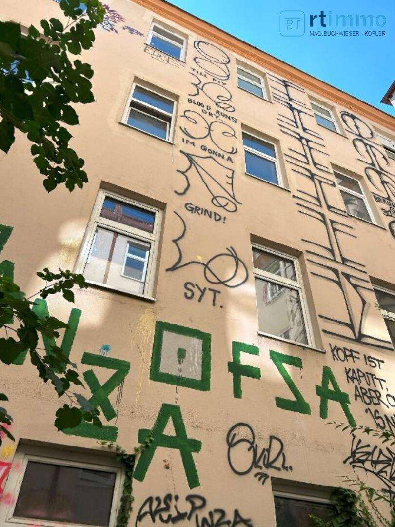 Schräge Ansicht der Innenhoffassade mit umfangreichen Graffiti und Fenstern, die den Renovierungsbedarf zeigen.