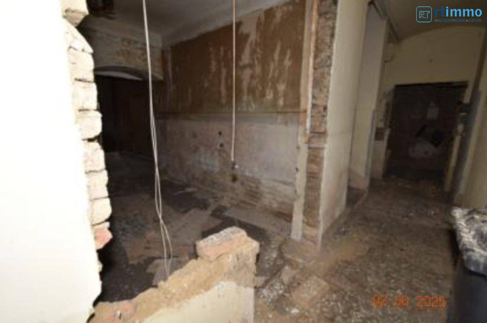 Innenraum im Rohbauzustand mit freigelegten Ziegelwänden und Bauschutt, bereit für die Sanierung.