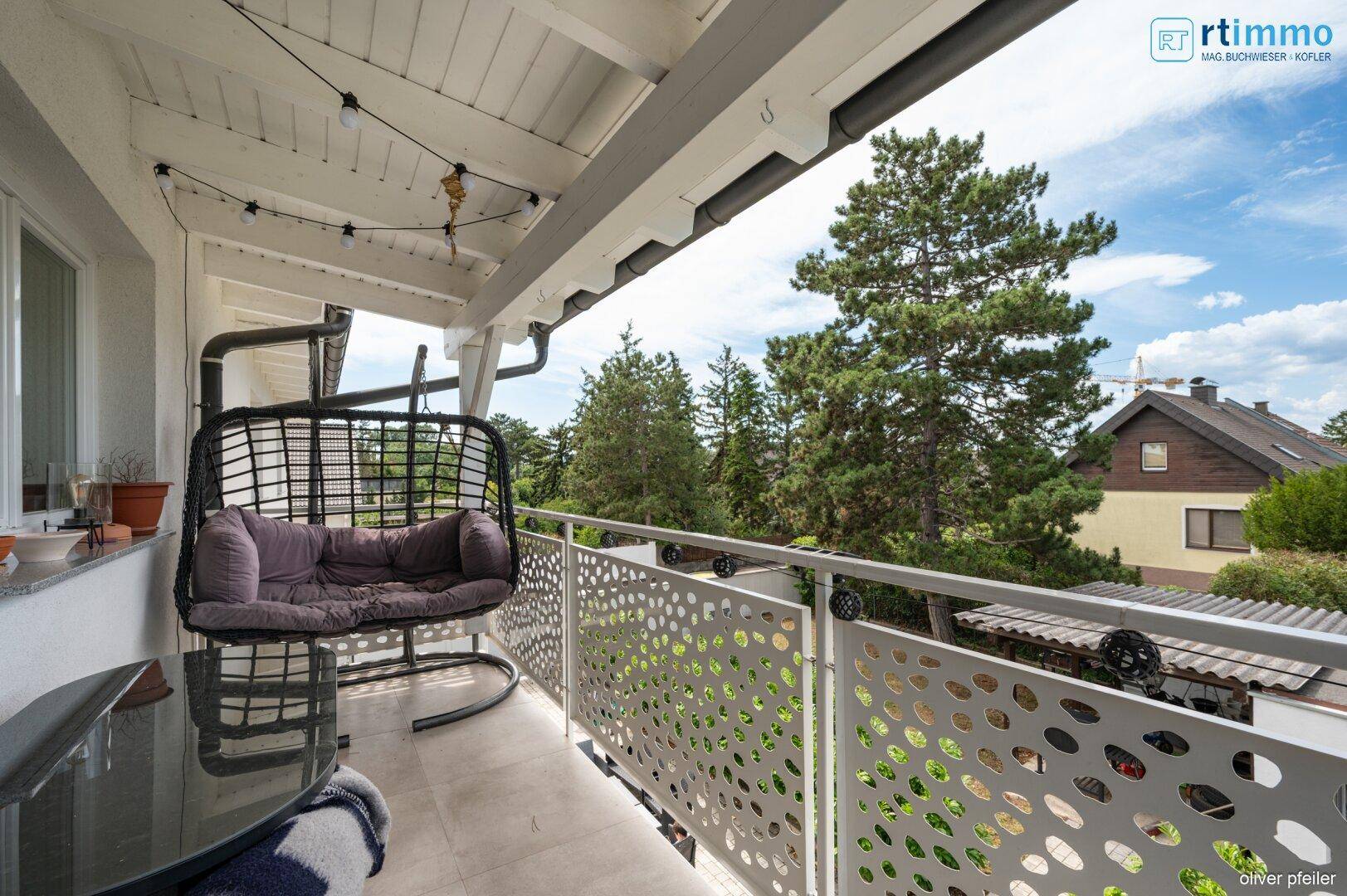 Gemütlicher Balkon mit Hängesessel und Blick ins Grüne sowie auf die Nachbarschaft.