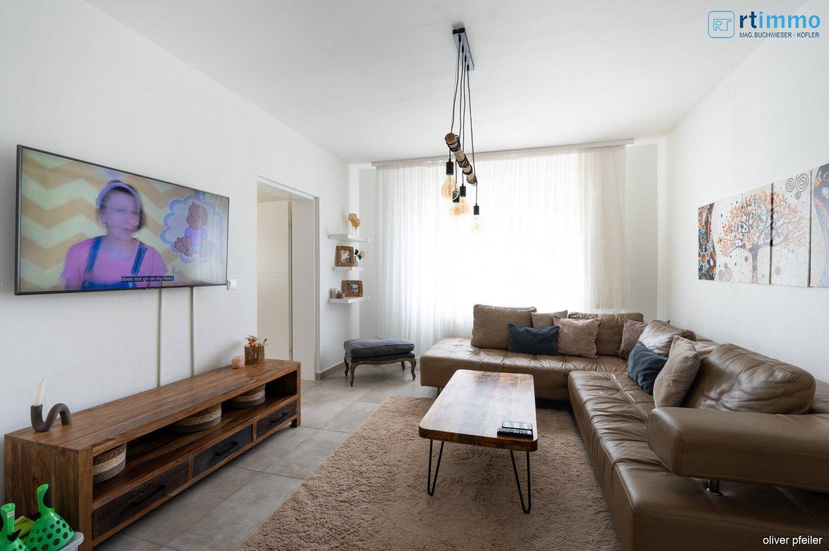 Geräumiges Wohnzimmer mit großem Ledersofa, Holztisch und Wandfernseher.